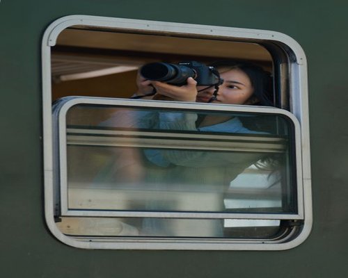 Someone looking out the window of a moving train, taking a break from their phone