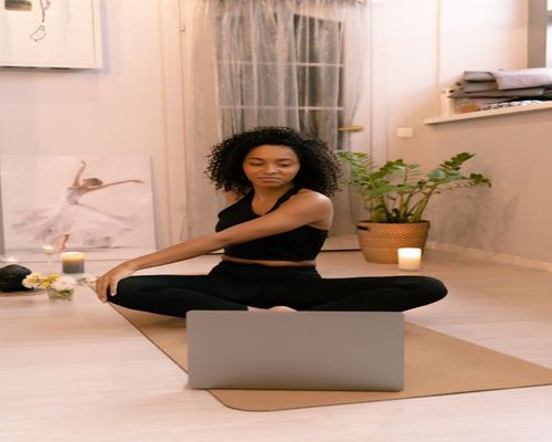 A person stretching their arms and looking away from multiple screens during an online class